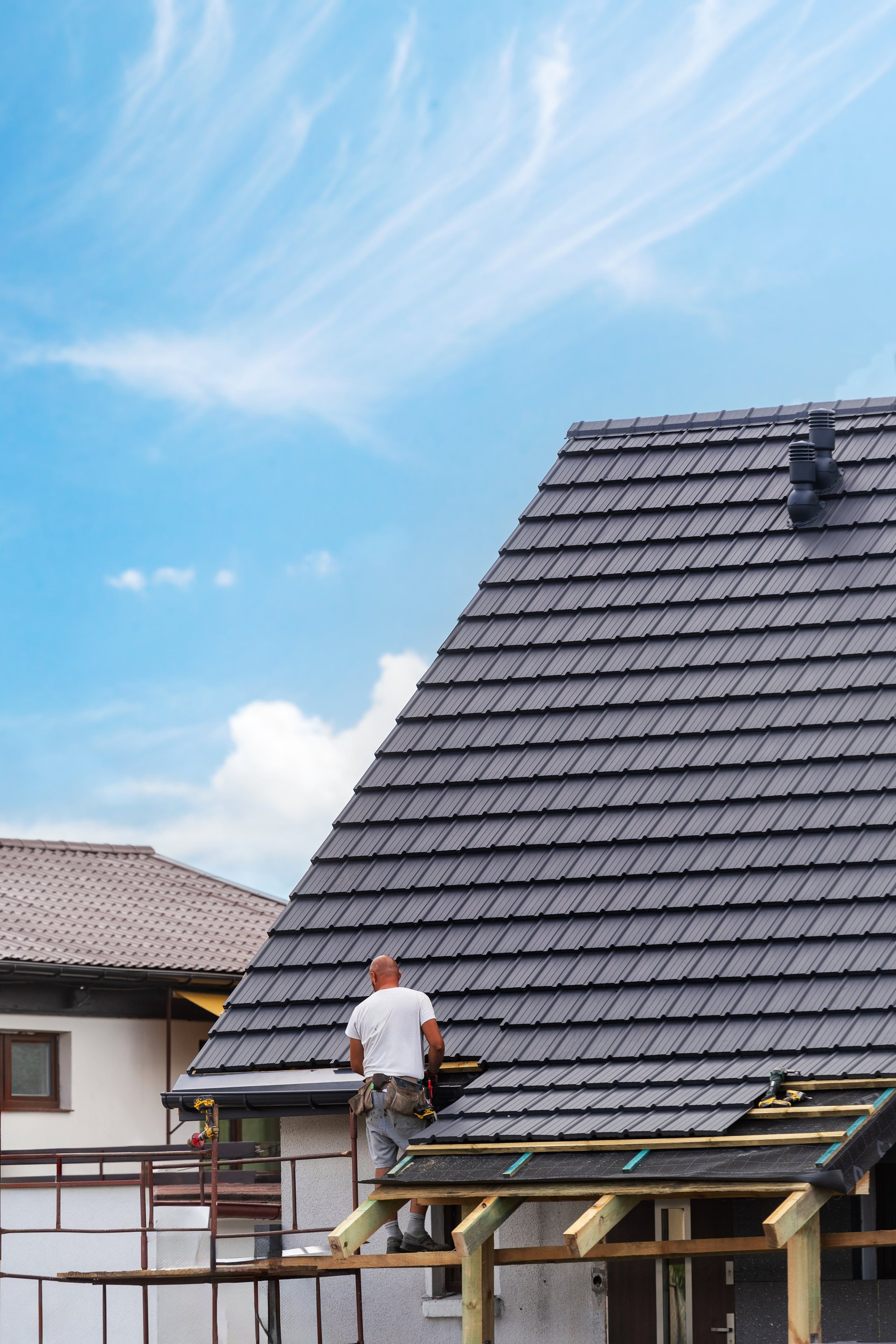 Professional roofer installing tiles on residential roof